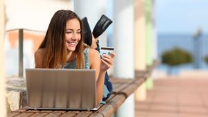 Pige med computer på bænk