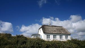 Hvidt hus med stråtag og blå himmel