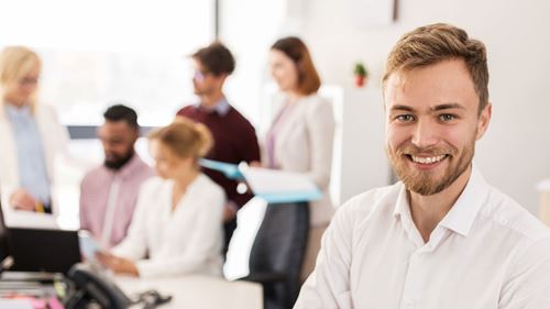 Mand mand med arbejdende folk ved computer i baggrunden