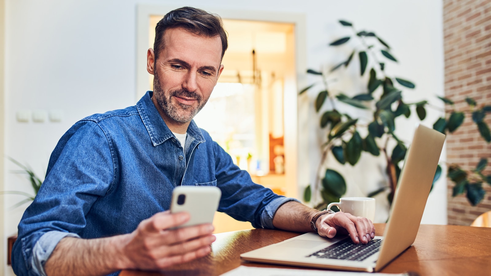 Mand med mobil og computer