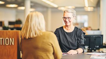 Kvindelig medarbejder betjener en kunde i en bank
