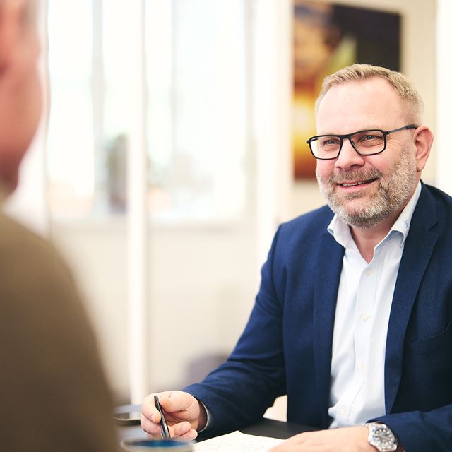 Erhvervsrådgiver holder møde og kigger på en person, der sidder med ryggen til